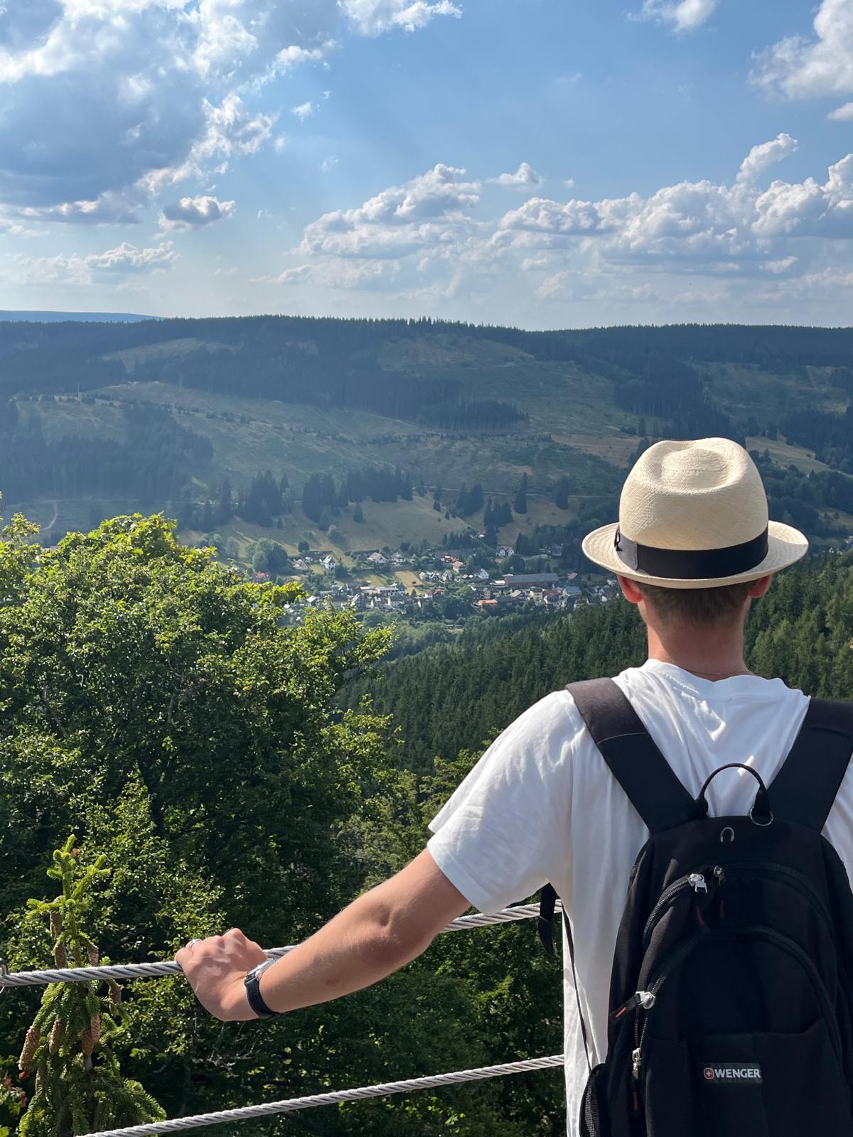 Wanderer mit Hut blickt ueber das Tal